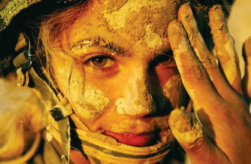 A female soldier has mud applied to her face for camouflage in this photo from an IDF Instructors course in 2006. (photo credit: IDF FLICKR)