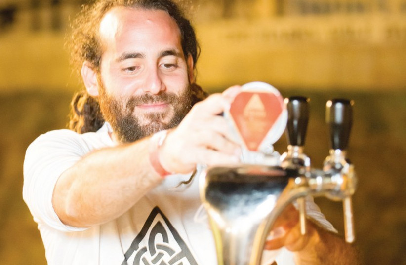 Or Fass, co-owner of the microbrewery Fass Beers on the Golan, pours a pale ale at the Jerusalem Beer Festival. (photo credit: IGOR FARBEROV)