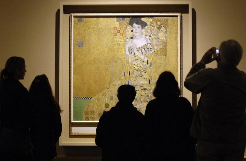 Museum visitors study "Adele Bloch-Bauer I," a 1907 painting by Austrian artist Gustav Klimt at a special exhibition of Klimt paintings looted by the Nazis during World War II.  (photo credit: REUTERS)