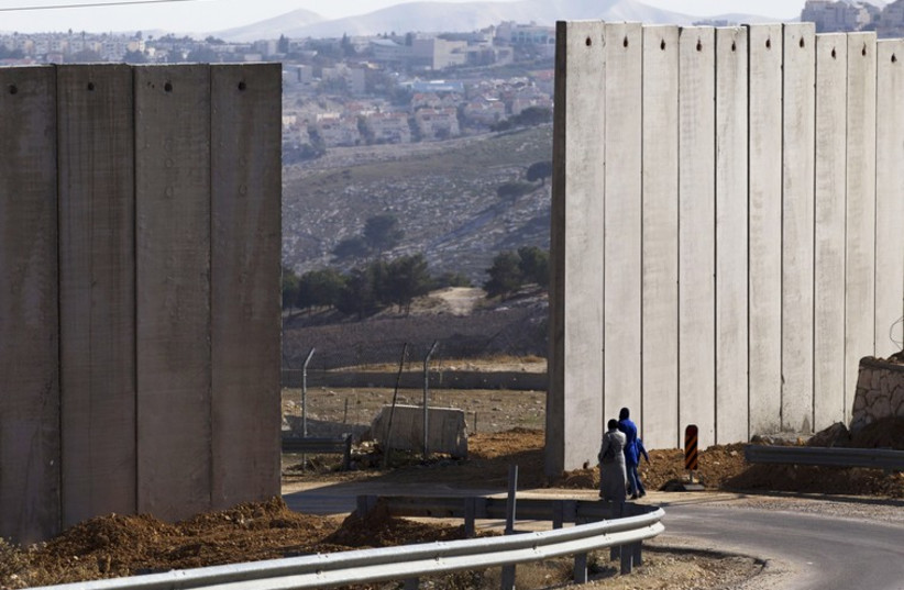 Palestinians walk near an opening in Israel's controversial barrier in the east Jerusalem neighbourhood of A-tur (photo credit: REUTERS)