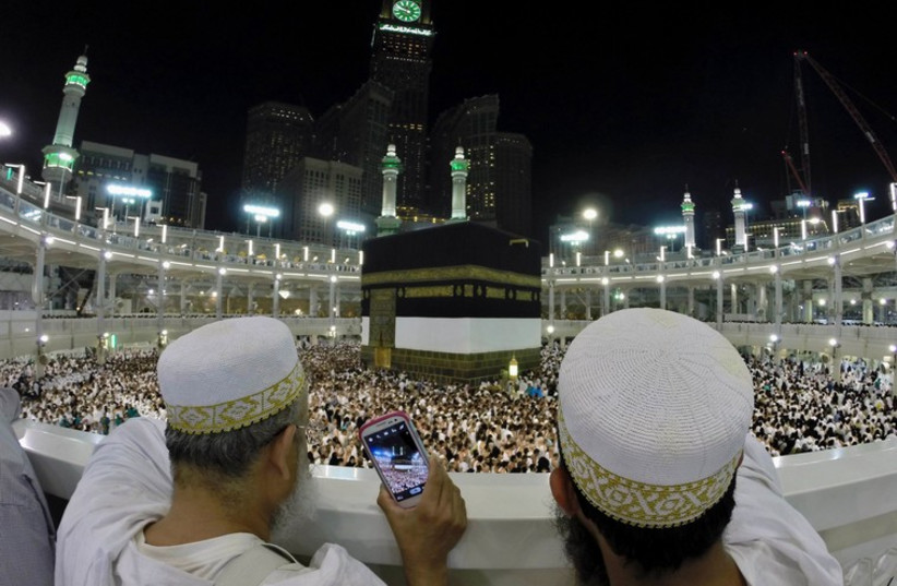 Muslim pilgrims take pictures for the pilgrims as they pray around the holy Kaaba at the Grand Mosque, during the annual hajj pilgrimage in Mecca (photo credit: REUTERS)