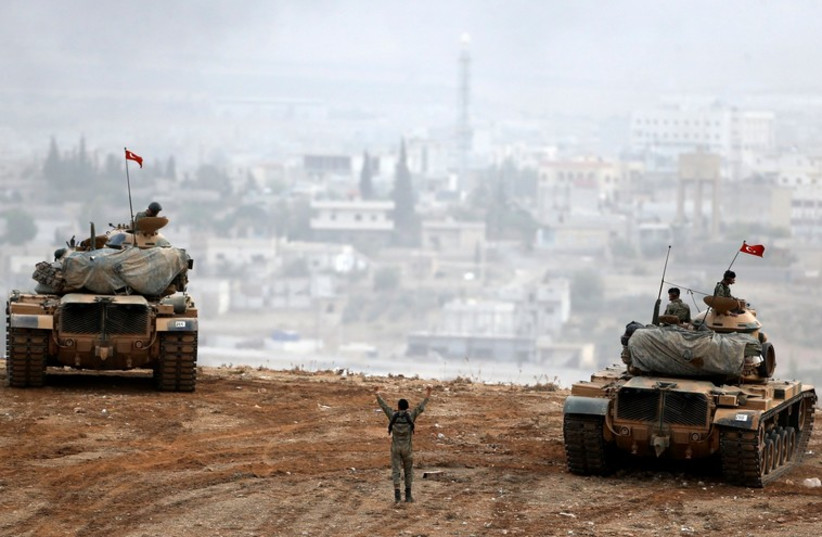 Turkish army tanks manoeuver as Turkish Kurds watch over the Syrian town of Kobani (photo credit: REUTERS)