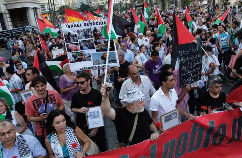 DEMONSTRATORS MARCH with Palestinian flags during a protest against the Israeli offensive against Gaza, in Valencia, Spain (photo credit: REUTERS)