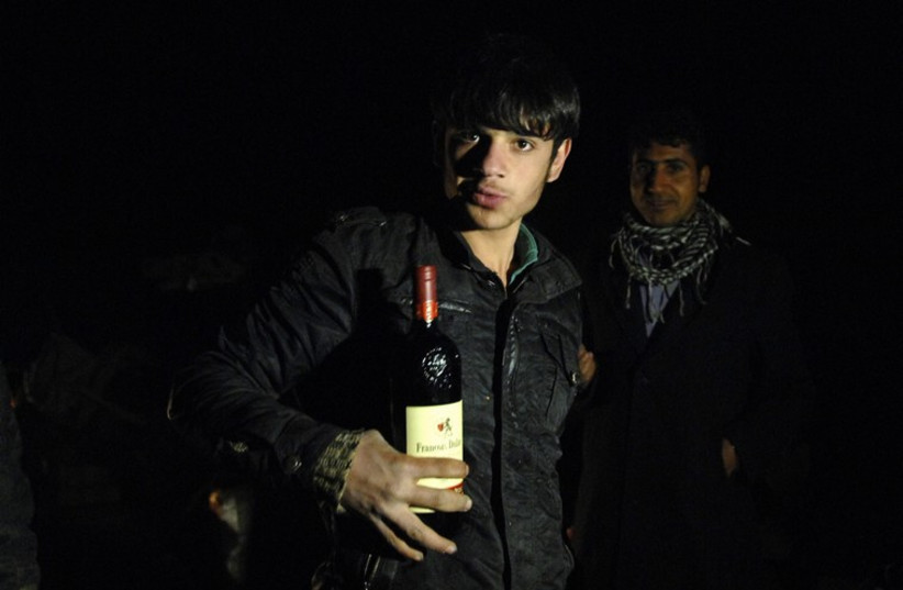 A smuggler poses with a bottle of wine during an alcohol smuggling operation to Iran (photo credit: REUTERS)