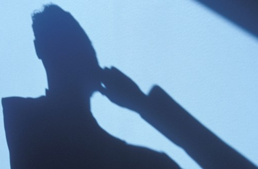 Shadowy figure uses cell phone (illustrative) (photo credit: INGIMAGE)