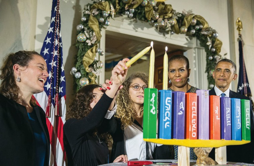 Barack Obama and first lady Michelle Obama as they light a Hanukka made by pupils from Jerusalem’s Hand in Hand school, at the White House. (photo credit: REUTERS)