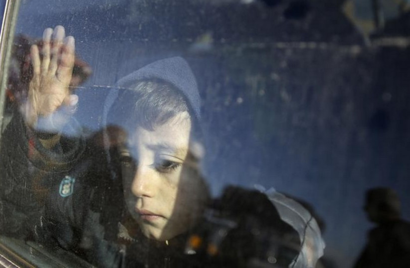 A Palestinian boy, hoping to cross into Egypt with his family, looks out a car window as he waits at the Rafah crossing between Egypt and the southern Gaza Strip (photo credit: REUTERS)