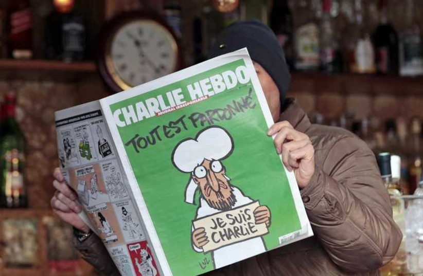 A man poses with the new issue of French satirical weekly Charlie Hebdo at a cafe in Nice. (photo credit: REUTERS)