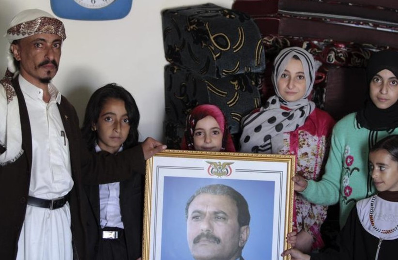 Chief rabbi of the Jews in Yemen Yahya Yosef Mosa with his family carries a picture of the ousted president of Yemen Ali Abdullah Salehin in his home in Sanaa (photo credit: REUTERS)