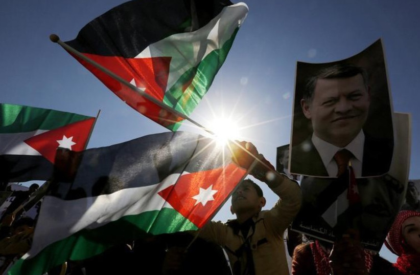 Protesters hold up pictures of Jordanian King Abdullah and pilot Muath al-Kasaesbeh with national flags (photo credit: REUTERS)