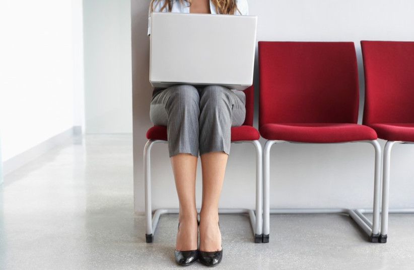Woman using laptop in office corridor  (photo credit: ING IMAGE/ASAP)