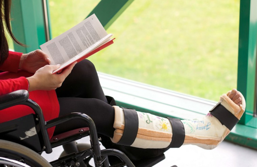 Young woman in a wheelchair with leg in plaster (illustrative). (photo credit: INGIMAGE)