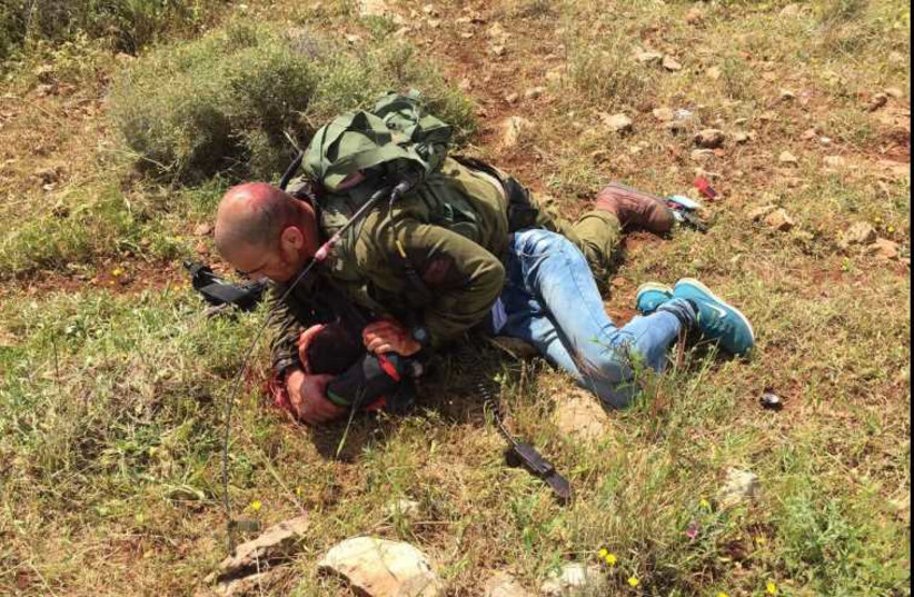 An IDF soldier subdues a Palestinian assailant after he was stabbed near a West Bank checkpoint (photo credit: IDF SPOKESMAN’S UNIT)