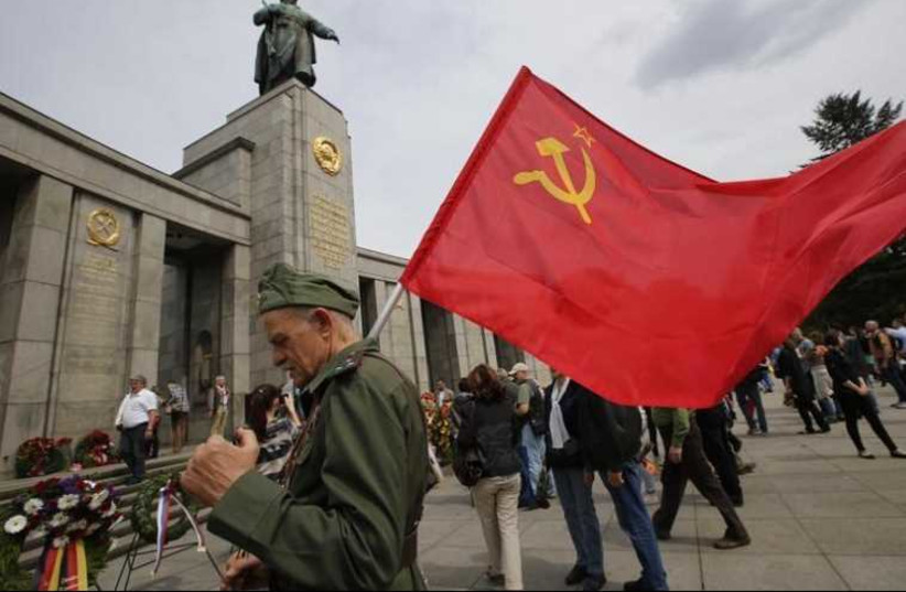 A man wearing a Red Army uniform holds a Soviet flag during celebrations to mark Victory Day at the Soviet War Memorial near the Reichstag building
