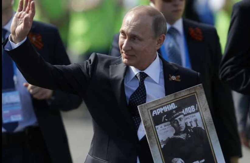Russian President Vladimir Putin holds the portrait of his father as he takes part in the Immortal Regiment march on the Red Square during the Victory Day celebrations in Moscow