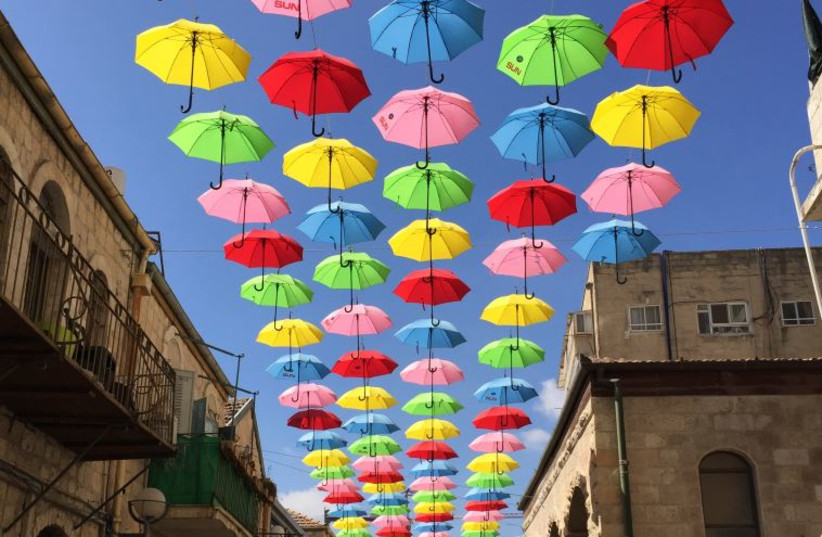 People walk under colourful umbrellas decorating a pedestrian mall in downtown Jerusalem June 30, 2015.