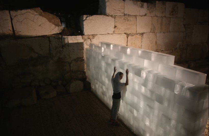An actress performs in front of a wall of ice – inspired by the work of American artist Allan Kaprow – at the Davidson Center near the Western Wall