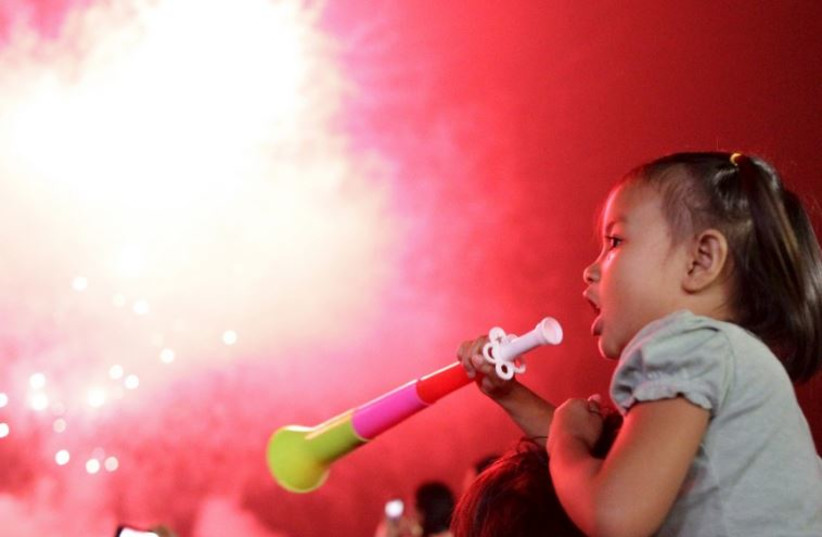 A girl blows a party horn at midnight during New Year celebrations in Manila, Philippines
