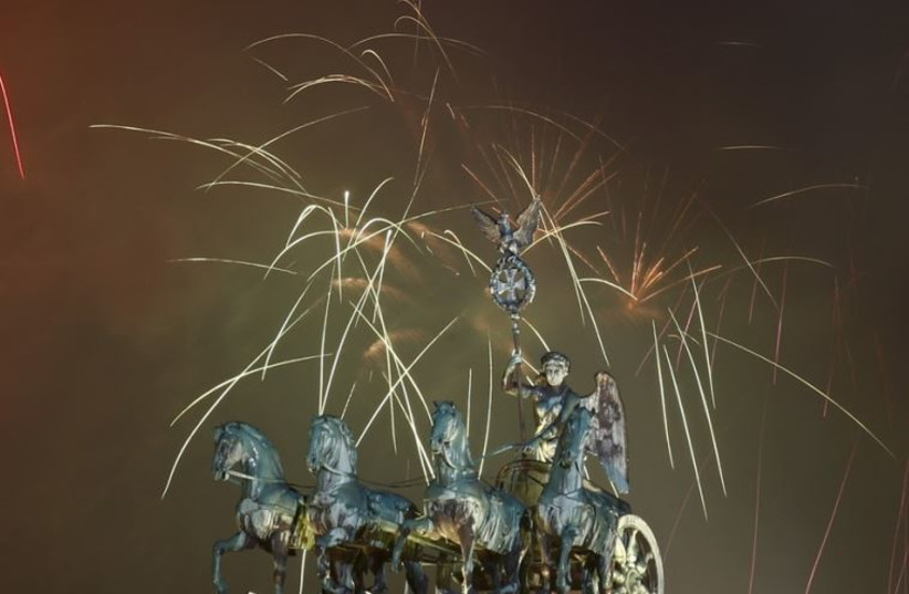 Fireworks explode next to the Quadriga sculpture atop the Brandenburg gate during New Year celebrations in Berlin
