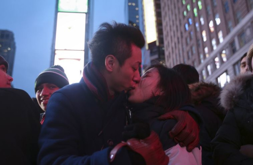 A couple kiss on the ground in a penned off area of Times Square before New Year's Eve celebrations begin in New York