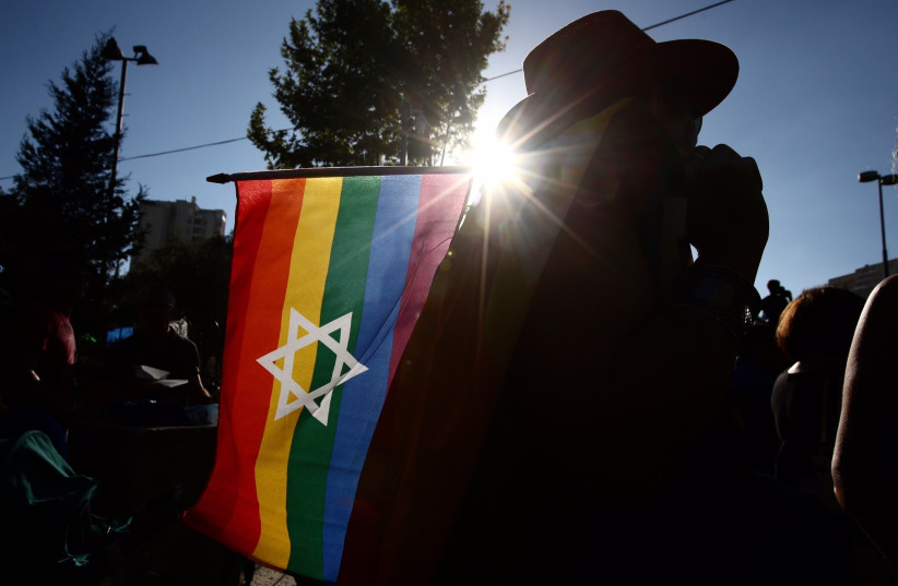 Man holds a Star of David rainbow flag at the 2017 Jerusalem Gay Pride Parade (photo credit: MARC ISRAEL SELLEM)
