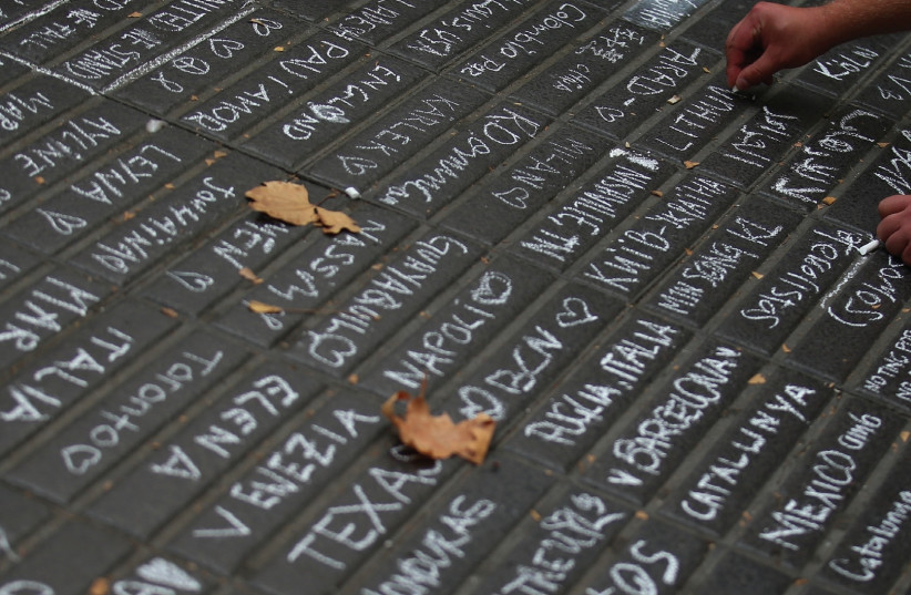 A PERSON writes messages on a sidewalk at Las Ramblas in Barcelona on Saturday (photo credit: REUTERS)