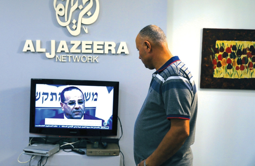 AN EMPLOYEE working inside the office of Qatar-based Al- Jazeera network in Jerusalem watches the news, last month. (photo credit: AMMAR AWAD / REUTERS)
