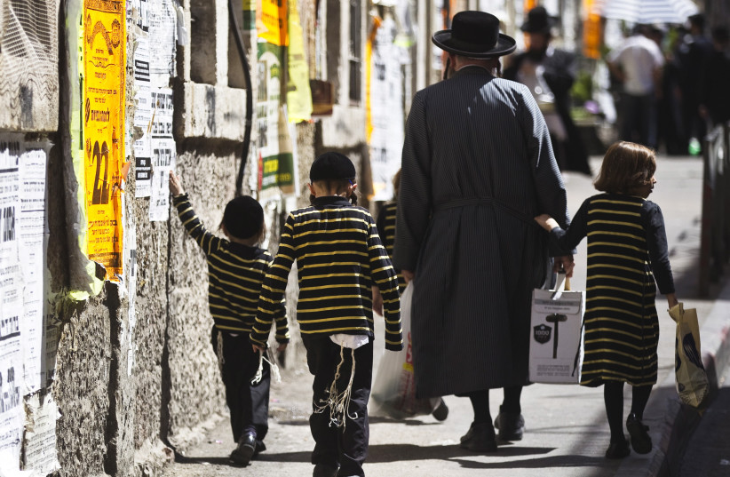 An ultra-Orthodox Jewish man walks with his children on a street in Jerusalem's Mea Shearim neighbourhood September 24, 2015. (photo credit: REUTERS)