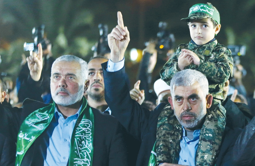 THE SON OF Hamas military leader Mazen Fuqaha sits on the shoulders of Hamas Gaza chief Yahya al-Sinwar as Hamas politburo chief Ismail Haniyeh gestures during a memorial service for Fuqaha in Gaza City in March. (photo credit: REUTERS)