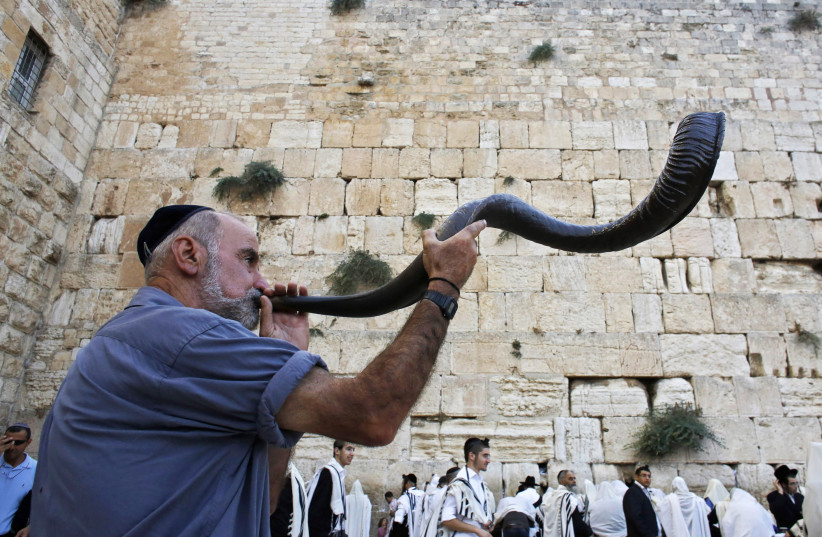 A Jewish worshipper blows a Shofar,  at the Western Wall ahead of Rosh Hashana (photo credit: AMMAR AWAD/REUTERS)