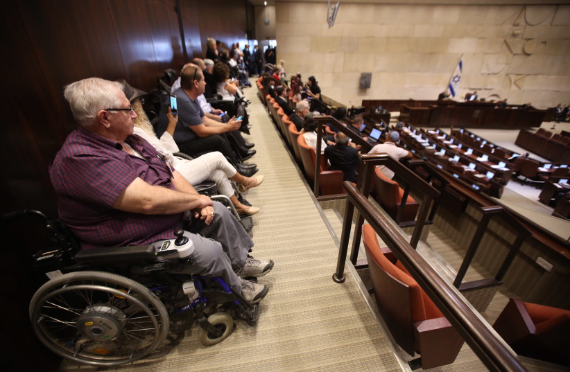 Disabled activists sit in at the Knesset plenum discussing goverment allowances for the disabled, September 18, 2017. (photo credit: MARC ISRAEL SELLEM/THE JERUSALEM POST)