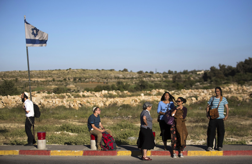 Israeli pedestrians stand on a roadside near the West Bank Jewish settlement of Efrat (photo credit: AMIR COHEN - REUTERS)