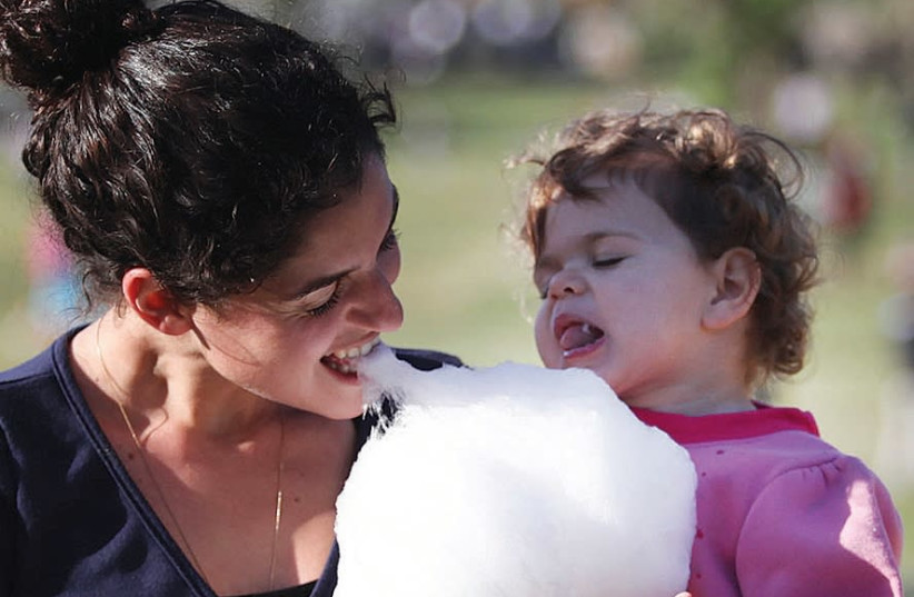 Mother and daughter enjoy cotton candy at Jewish holiday festivities.  (credit: MARC ISRAEL SELLEM/THE JERUSALEM POST)