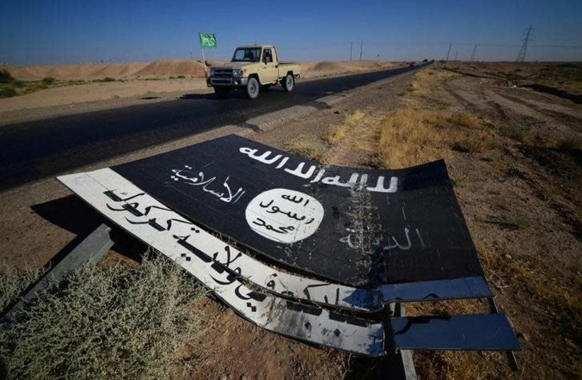 A black sign belonging to Islamic State militants is seen on the road in Al-Al-Fateha military airport south of Hawija, Iraq, October 2, 2017. (photo credit: REUTERS/STRINGER)