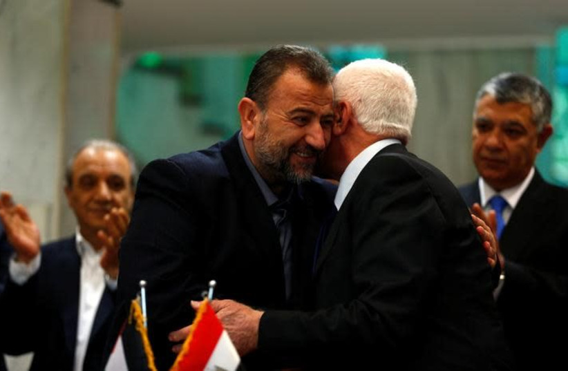 Head of Hamas delegation Saleh Arouri hugs Fatah leader Azzam Ahmad as they sign a reconciliation deal in Cairo, Egypt, October 12, 2017. (photo credit: REUTERS/AMR ABDALLAH DALSH)