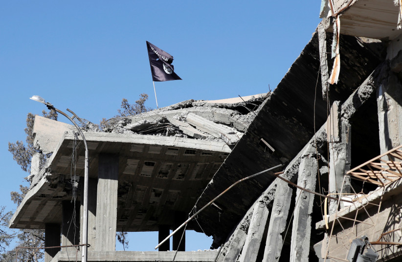 A flag of Islamic State militants is pictured above a destroyed house near the Clock Square in Raqqa (photo credit: ERIC DE CASTRO/ REUTERS)