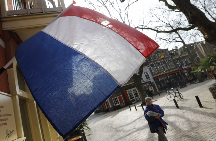 A woman walks past a national flag, the day before a general election, in Delft, Netherlands, March 14, 2017. (credit: REUTERS)