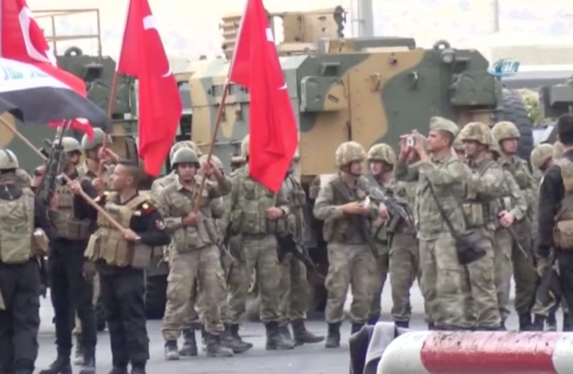 Iraqi and Turkish soldiers wave flags at the Habur Border Gate between Turkey and Iraq (photo credit: IHA/ VIA REUTERS)
