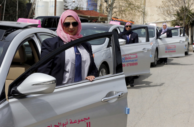 Female taxi drivers pose for a photo in front of their vehicles at Noor Jordan for Transport — Taxi Moumayaz's (Special Taxi) parking lot in Amman, Jordan, March 24, 2016. (photo credit: MUHAMMAD HAMED / REUTERS)