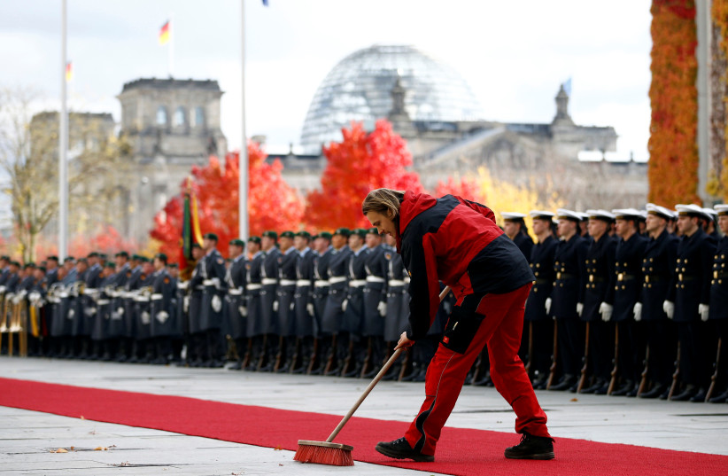 An employee of the chancellery sweeps the red carpet in front of the honour guard before a welcoming ceremony at the chancellery in Berlin, Germany November 2, 2016.  (photo credit: REUTERS)