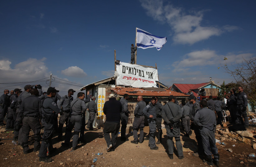 Border police remove an Israeli flag from a condemned building in Netiv Ha'avot (photo credit: MARC ISRAEL SELLEM)