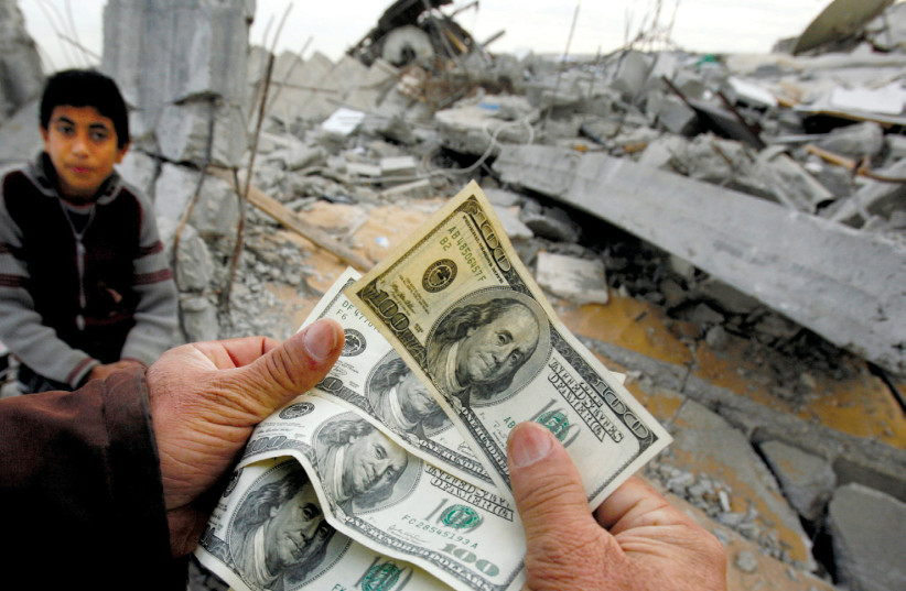 A PALESTINIAN whose house was destroyed by an Israeli air strike shows money distributed by Hamas in Jabalya in the northern Gaza Strip in 2009 (photo credit: SUHAIB SALEM / REUTERS)