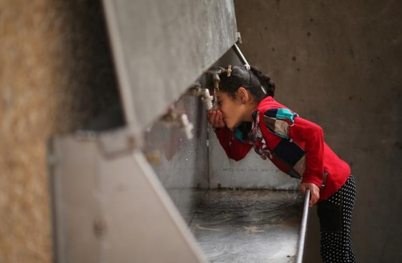 A Palestinian girl drinks from a public tap at the Jabaliya refugee camp in the Gaza Strip (photo credit: MOHAMMED SALEM/ REUTERS)