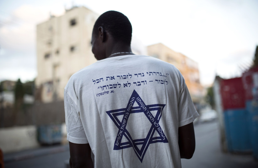 An African migrant wears a T-shirt with a Hebrew phrase referring to the Holocaust," I promise to remember... and never forget!" in south Tel Aviv July 17, 2013. (photo credit: REUTERS)