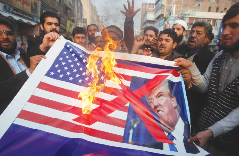 PEOPLE BURN a sign depicting a US flag and a picture of US President Donald Trump as they take part in a rally in Peshawar, Pakistan, last week. (Fayaz Aziz/Reuters) (photo credit: REUTERS/ FAYAZ AZIZ)