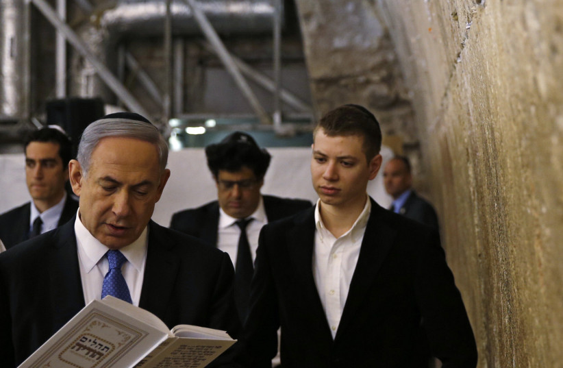 Yair Netanyahu observes his father Israeli Prime Minister Benjamin Netanyahu reading a prayer at the Western Wall in Jerusalem's Old City (photo credit: RONEN ZVULUN/REUTERS)