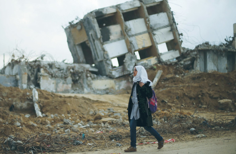 ДЕВУШКА ПРОХОДИТ мимо развалин дома на севере сектора Газа, разрушенного во время операции «Несокрушимая скала». (Фото: МОХАММЕД САЛЕМ/РЕЙТЕР)
