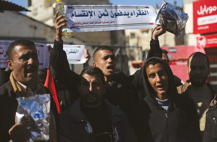 Palestinians protest poor living conditions at UNRWA’s Rafah office in the southern Gaza Strip. (Sign: The poor pay the costs of division) (photo credit: RADI RUBINSTEIN)