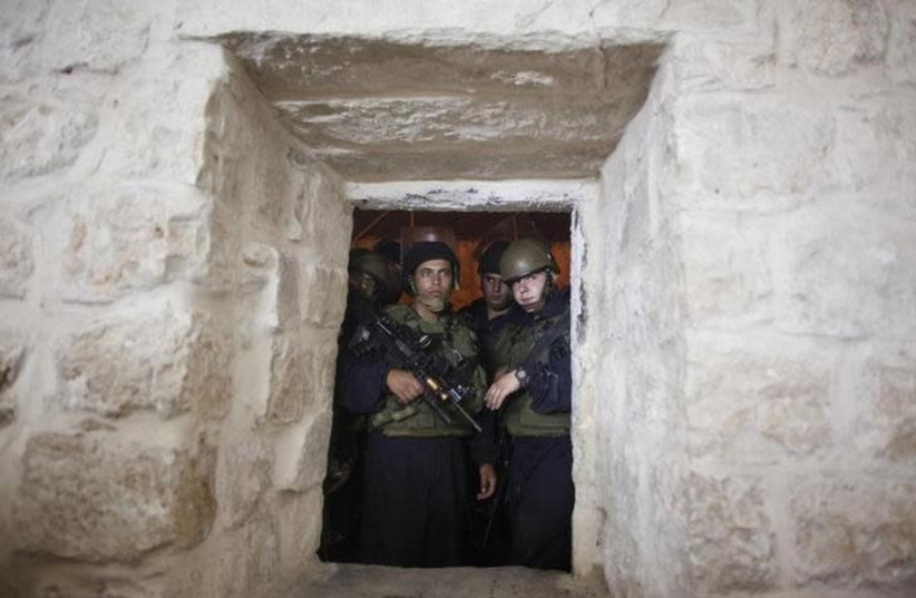 Israeli soldiers stand guard at a window hole at Joseph's Tomb as Jewish worshippers pray inside it, in the West Bank city of Nablus, early July 4, 2011 (photo credit: REUTERS/NIR ELIAS)