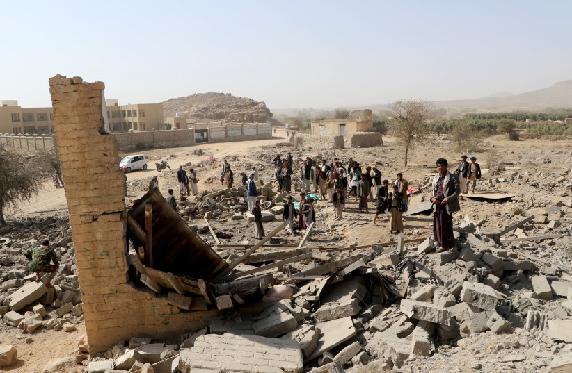 People gather at the site of an air strike that destroyed a house on the outskirts of the northwestern city of Saada, Yemen January 22, 2018. (photo credit: NAIF RAHMA / REUTERS)